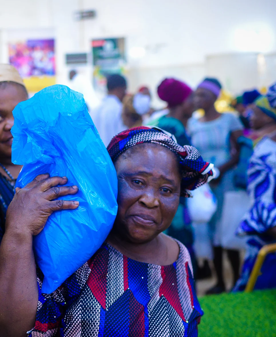 An older woman smiles as she carries her gift bag at the Foundation&rsquo;s widows&rsquo; outreach in Akute.