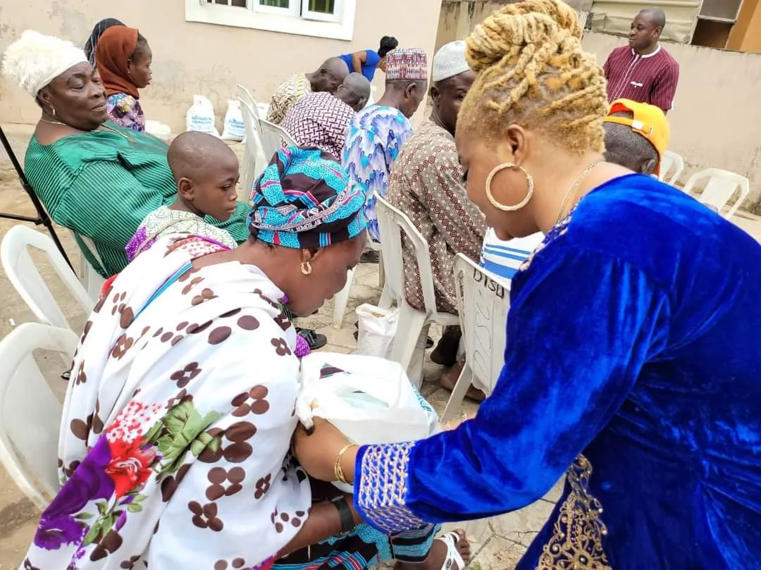 A volunteer handing a gift bag to an older woman seated outdoors.