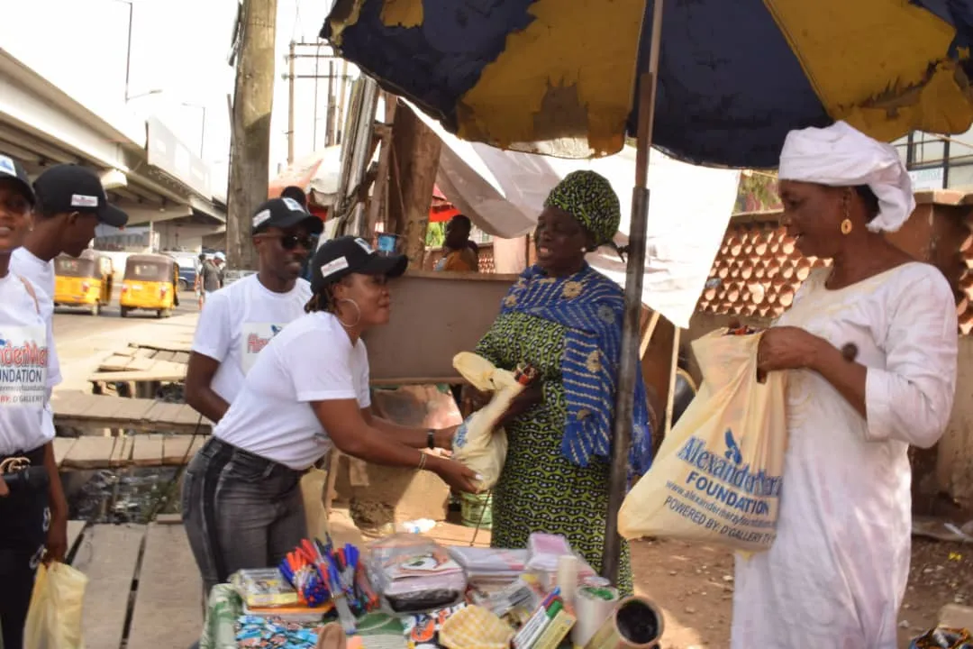 A volunteer handing a bag of goods to a woman at a market stall.