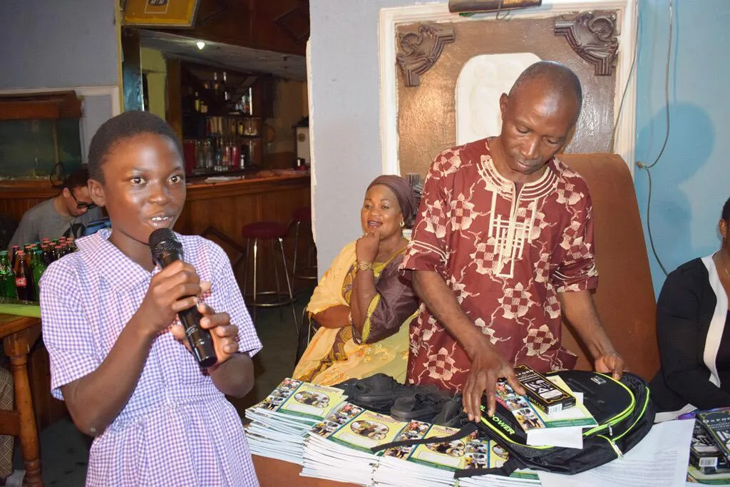 A schoolgirl speaking into a microphone at a student scholarship event.