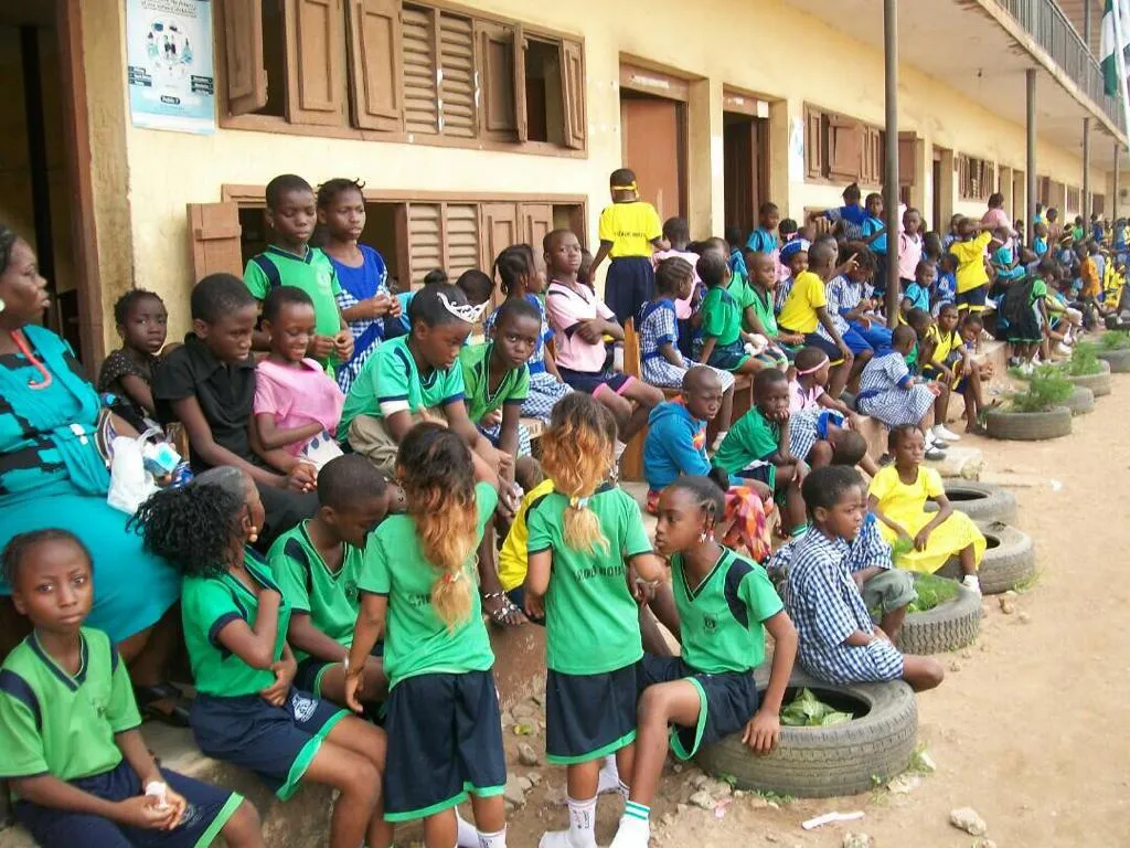Pupils in green and white uniforms gathered in a school yard.
