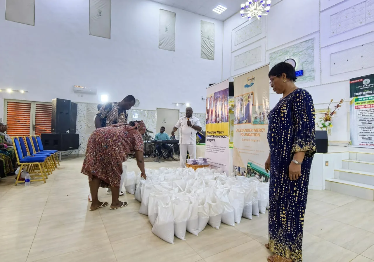 A woman bends to pick up a bag of food at a Foundation outreach while another looks on.